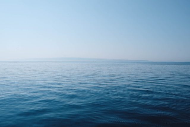 eine relativ ruhige meeresoberfläche mit kleinen quadratischen wellen. im hintergrund sieht  man den horizont.